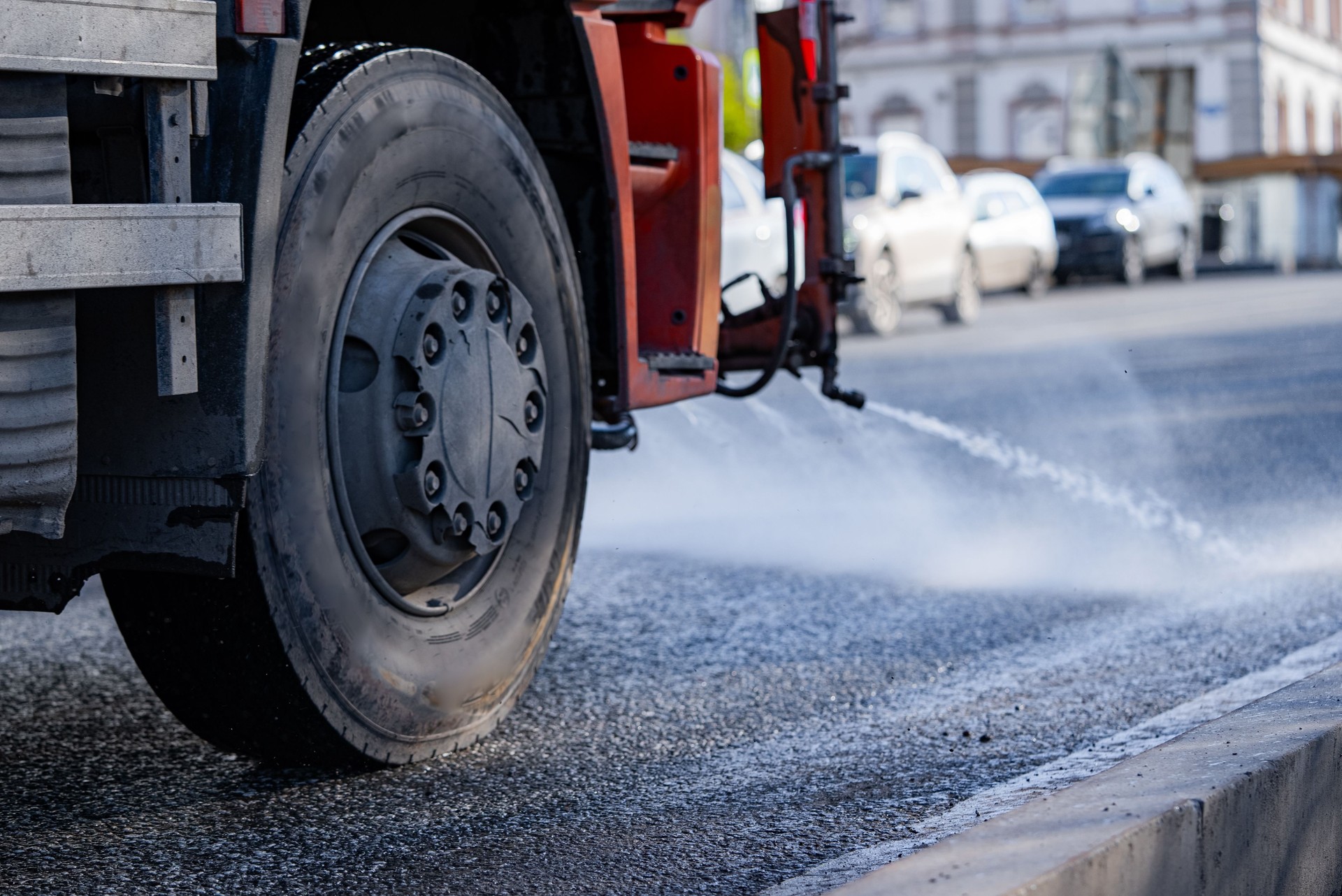 Street cleaning truck spraying water across asphalt road on a sunny summer day, revitalizing the city while effectively removing dust and debris for enhanced urban hygiene