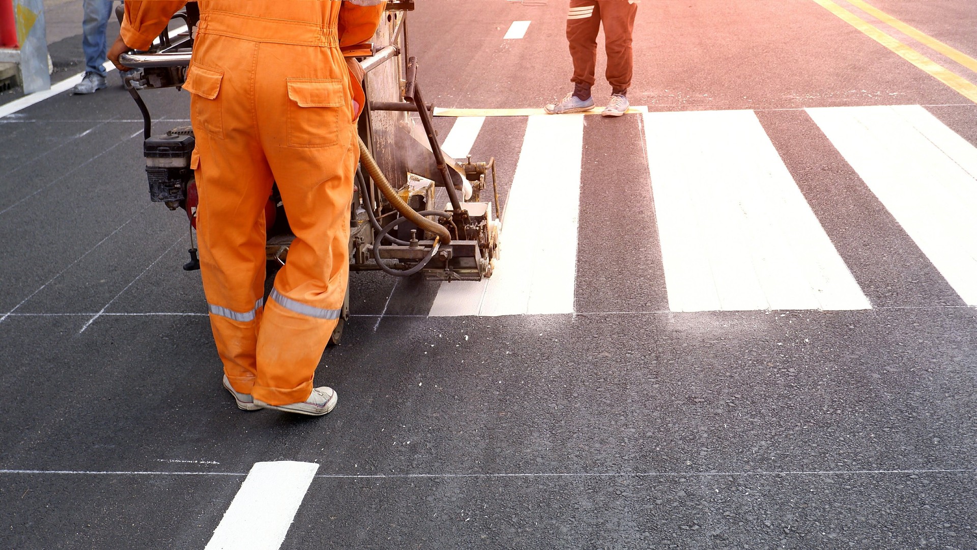 Road worker painting crosswalk on asphalt road